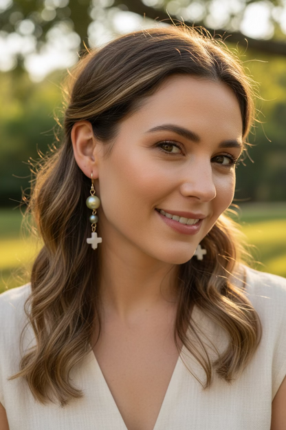 Close-up flat lay with light green and teal pearl beads and white cross drops on gold-filled wire