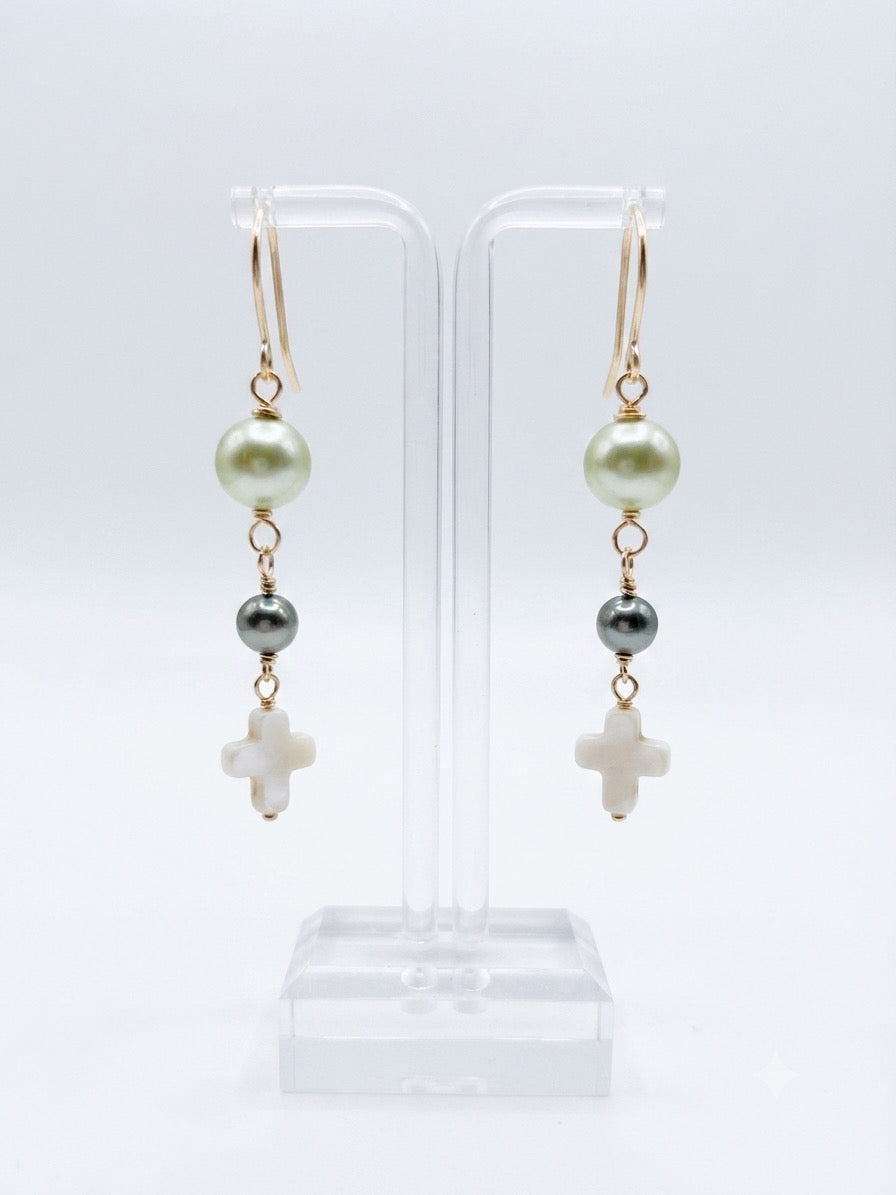 Earrings on display stand showing white and gray pearl beads with cross pendant on gold-filled wire
