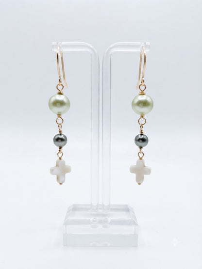Earrings on display stand showing white and gray pearl beads with cross pendant on gold-filled wire