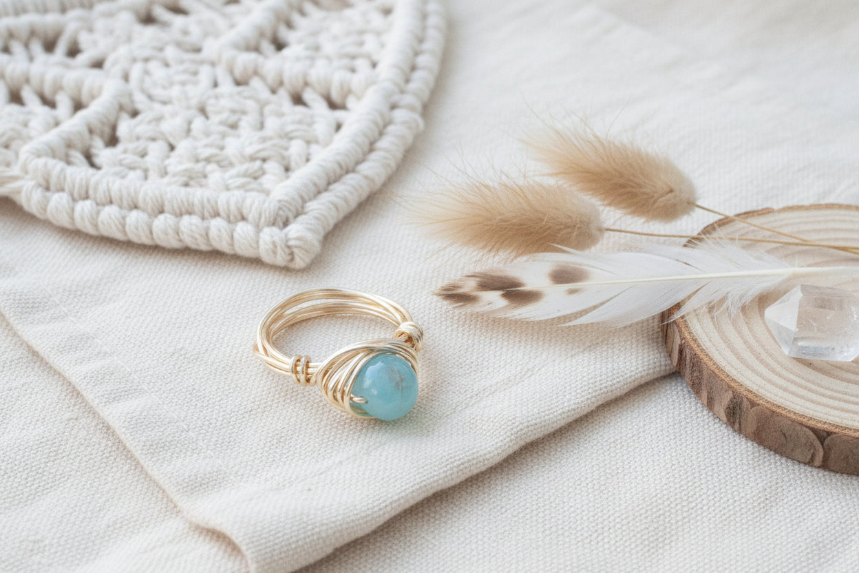Gold wire-wrapped ring with a turquoise stone on a textured surface