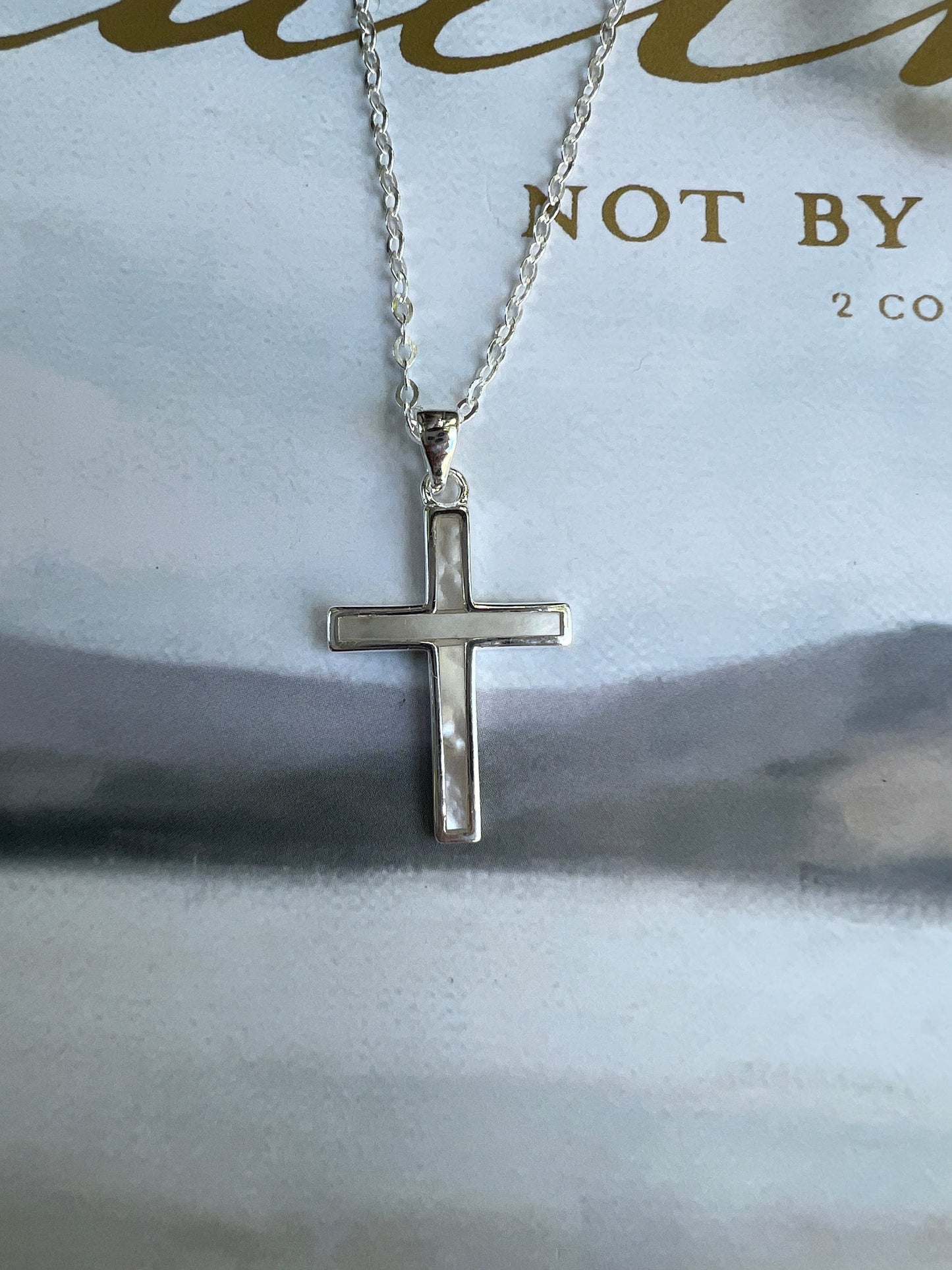 Sterling silver mother of pearl cross necklace on white background