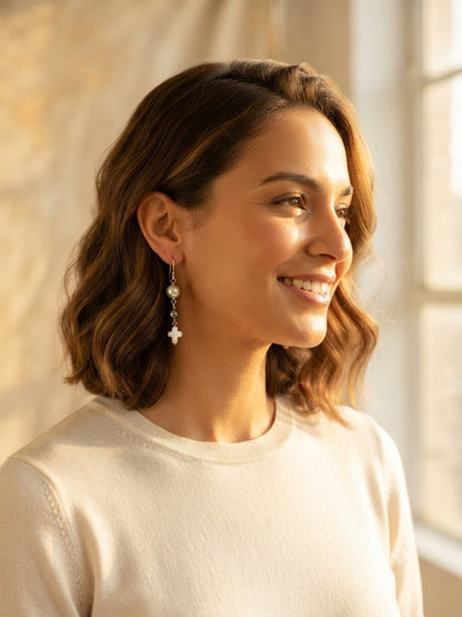 Woman wearing pearl cross dangle earrings with gray pearl beads and white cross drop